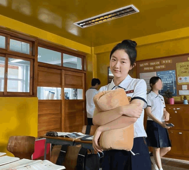 a girl in a school uniform holds a stuffed animal