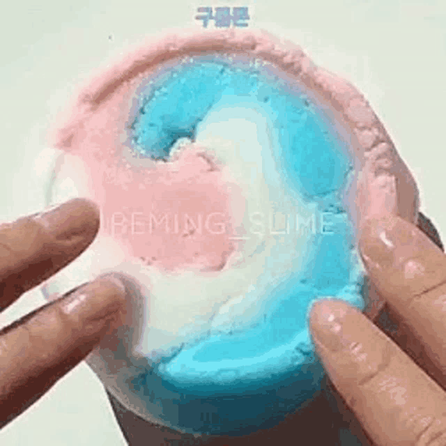 a person is holding a pink , white and blue slime .