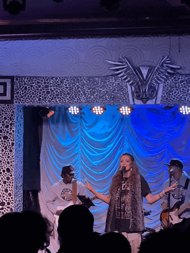 a woman singing into a microphone while a man plays a guitar