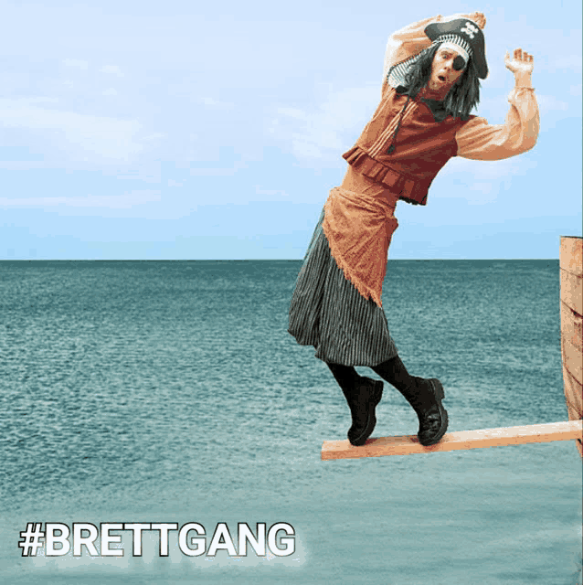 a man in a pirate costume is balancing on a wooden plank over the ocean