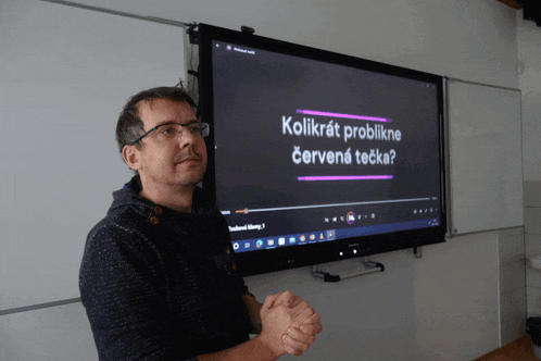 a man stands in front of a large screen that says kolikrát problikne cervena tecka