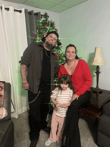 a family poses in front of a christmas tree in a living room