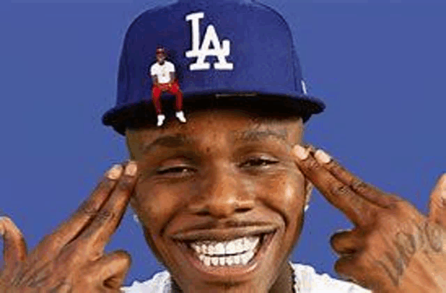 a man wearing a la hat is smiling and holding his hands to his head .