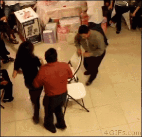 a man in a red shirt is dancing in front of a table with a box that says ' baby einstein ' on it