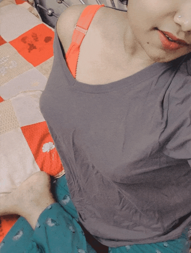 a woman laying on a bed wearing a gray shirt and a red bra