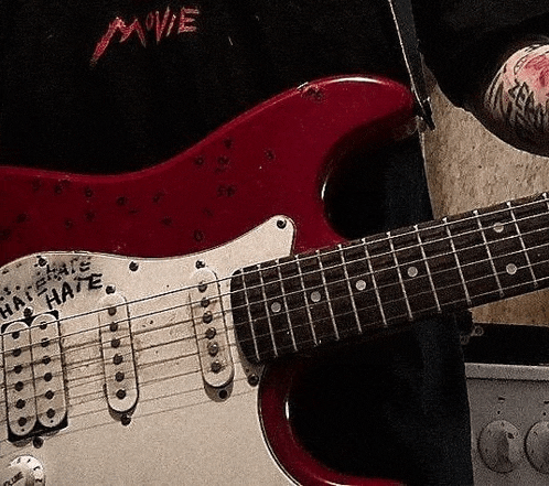 a red electric guitar has a sticker that says hate on it