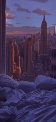 a bed with a view of a city skyline with the empire state building in the distance