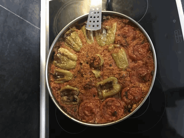 a pan of food with tomatoes and peppers on a stove