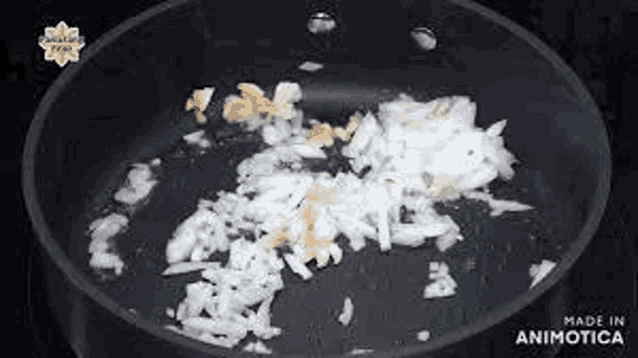 chopped onions and garlic are being cooked in a pan on a stove .