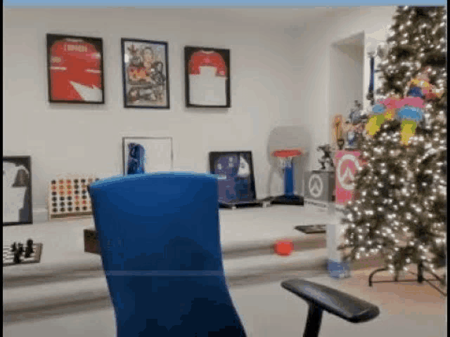 a blue chair is sitting in a living room with a christmas tree .