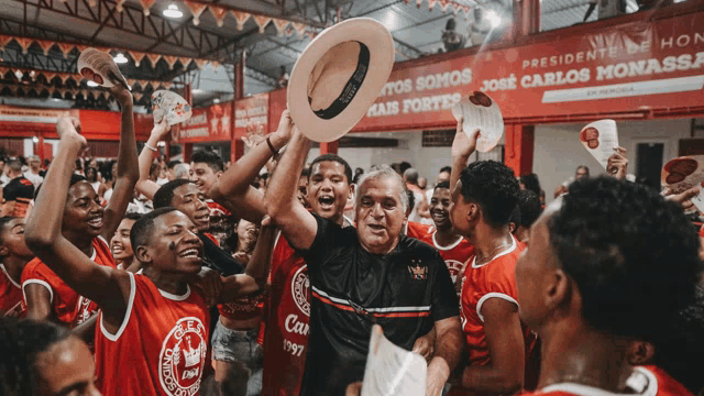 a man holding a hat in front of a banner that says presidente jose carlos monal