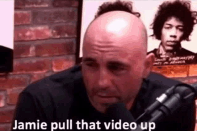 a bald man is sitting in front of a microphone with the words jamie pull that video up written on it .