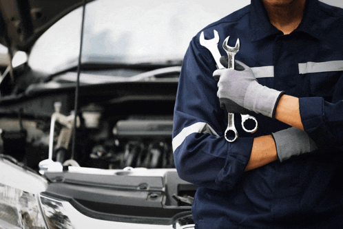 a man is holding a wrench in front of a car with the hood open