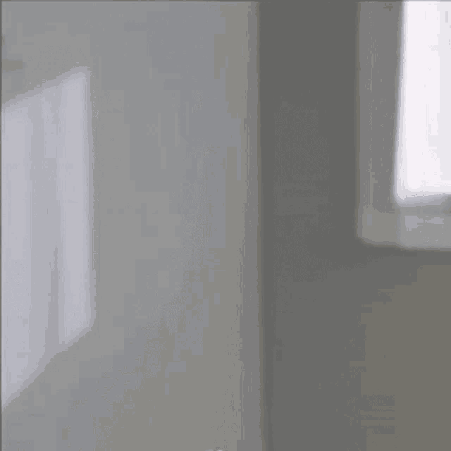 a blurred image of a room with a window and a white wall .