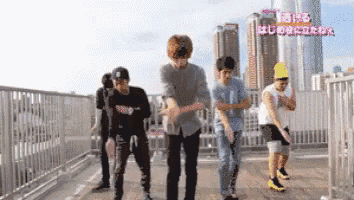 a group of young men are dancing on a balcony in front of a sign that says ' tokyo '