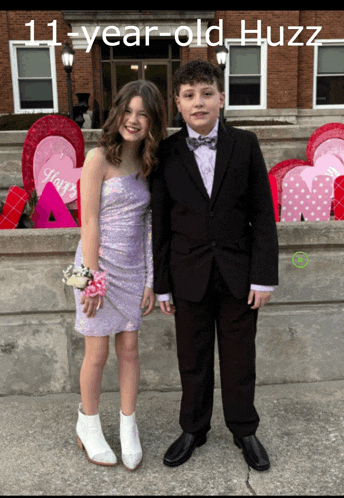 a girl in a purple dress and a boy in a tuxedo are posing for a picture with the caption 11 year old huzz