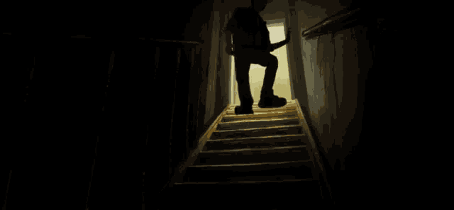 a person is walking down a set of stairs in a dark room