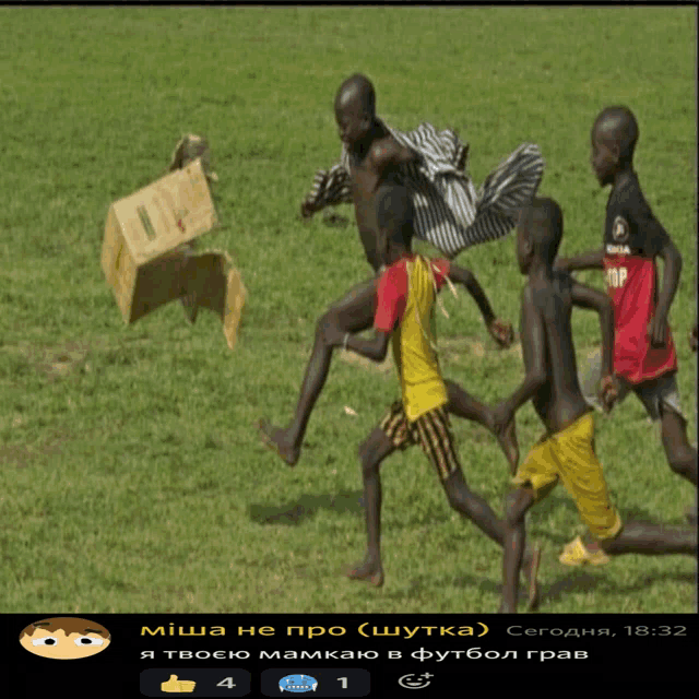 a group of boys are playing soccer on a field with a cardboard box in the background