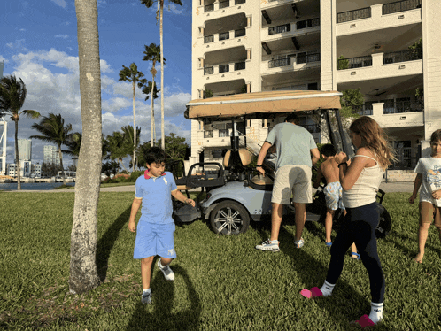 a group of children are standing around a golf cart