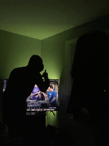 a silhouette of a man standing in front of a tv with a green light behind him