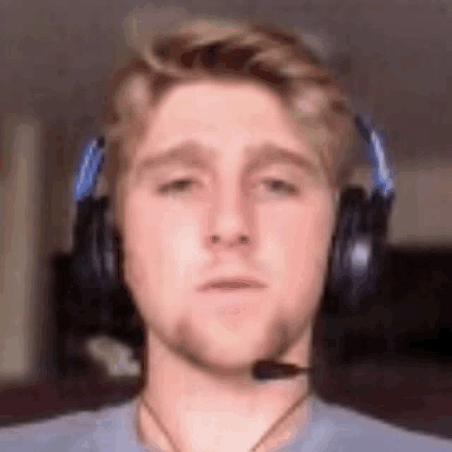 a young man wearing headphones and a microphone is looking at the camera .