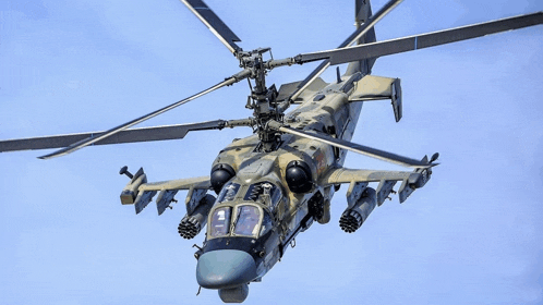 a military helicopter is flying in the sky with missiles attached to it