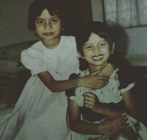 two little girls are posing for a picture and one has a bindi on her forehead