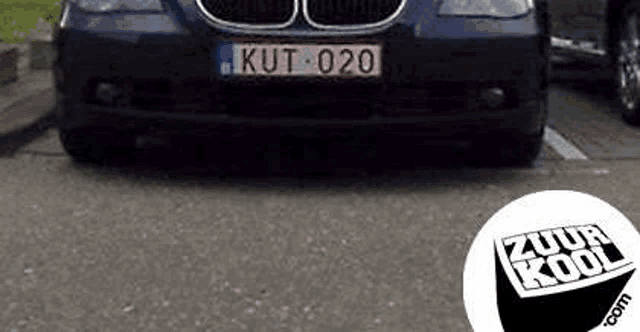 the front of a blue bmw with a license plate that says kut 020 is parked on the side of the road .