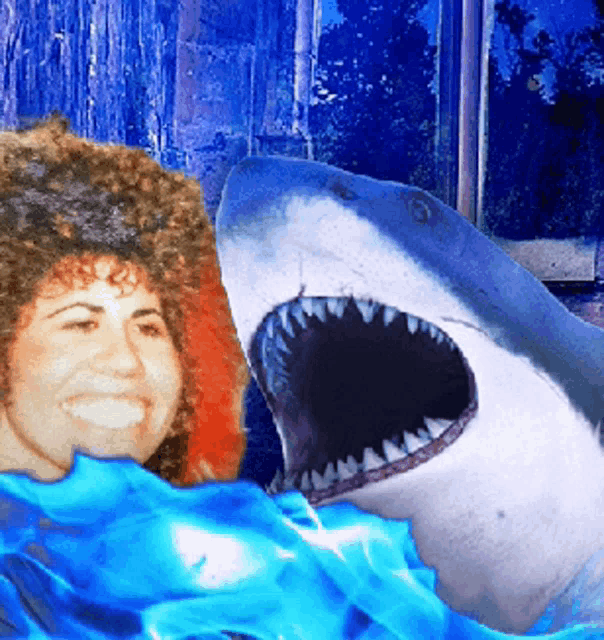 a woman is smiling in front of a shark with its mouth wide open