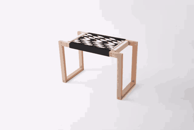 a small wooden stool with a black and white pattern on it