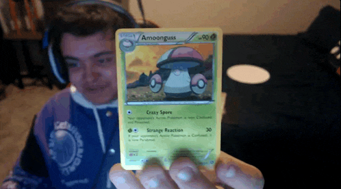 a man wearing headphones is holding up a pokemon card that says amoonguss