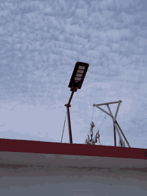 a street light on top of a red roof with a blue sky in the background