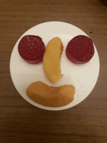 a white plate with a face made out of fruits