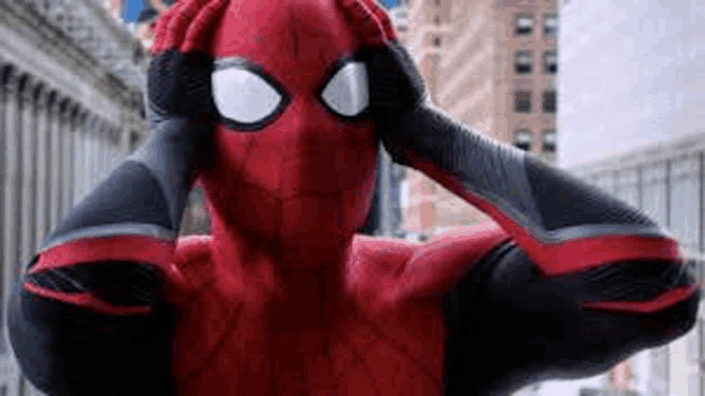 a close up of a person in a spiderman costume covering his ears with his hands .