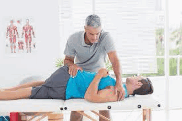 a man is laying on a table getting a massage from a man .