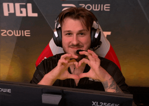 a man sitting in front of a xl2566k monitor making a heart shape with his hands