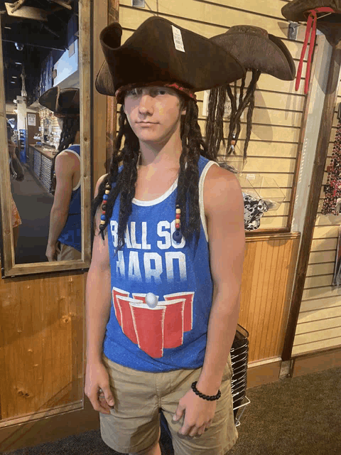 a young man wearing a pirate hat and a tank top that says ball so hard