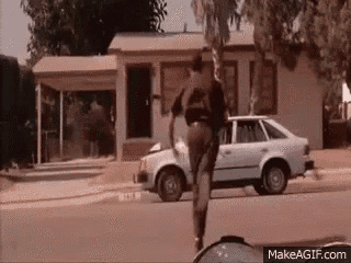 a man is standing next to a car on the side of the road in front of a house .