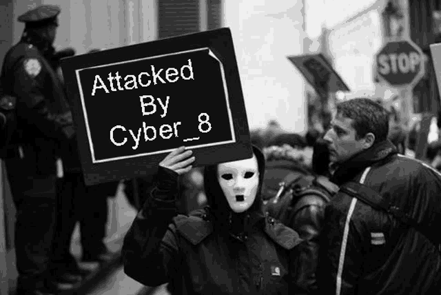 a person in a mask holds a sign that says attacked by cyber 8