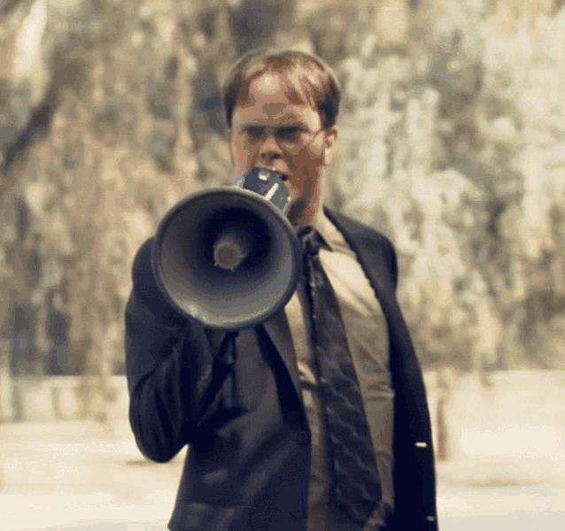 a man in a suit and tie is holding a megaphone to his mouth