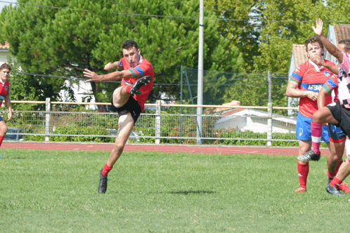 a soccer player wearing a red jersey that says ' aegon ' on it is kicking the ball