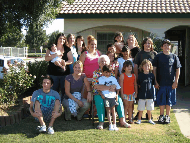 a group of people posing in front of a house with one boy wearing a t-shirt that says jd