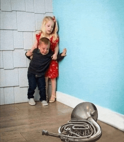 a boy and a girl standing next to a french horn