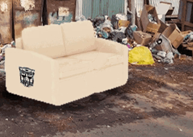 a couch with a transformer sticker on it sits in a pile of trash