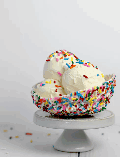 three scoops of ice cream in a bowl with sprinkles on top