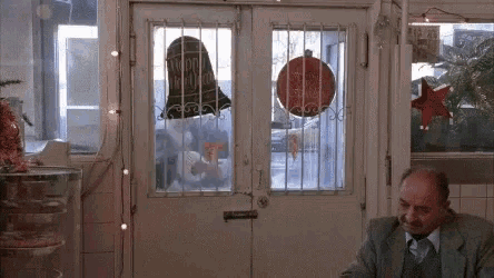 a man in a suit and tie is sitting at a table in front of a door with bars on it .