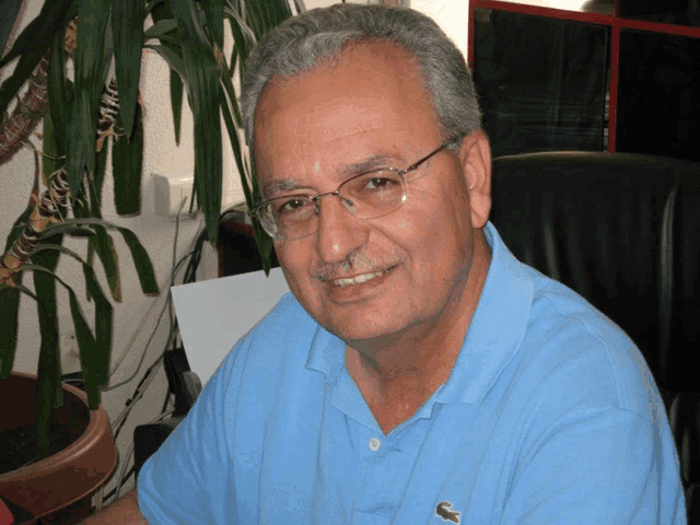 a man wearing glasses and a blue shirt has a lacoste logo on his chest