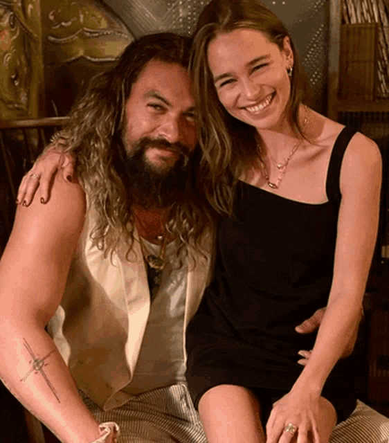 a man with a beard and a woman in a black dress are posing for a photo