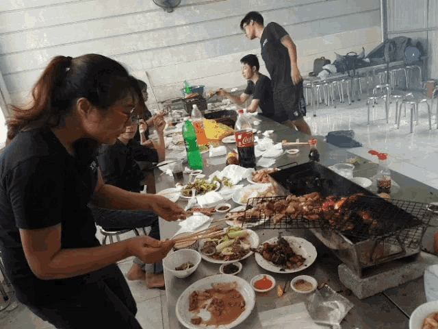 a group of people are sitting around a table with plates of food and a coca cola bottle on it