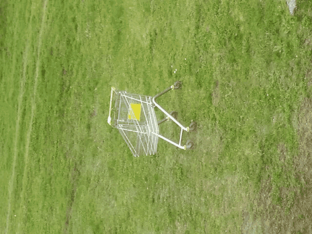 a shopping cart in a grassy field with a yellow sign that says ' trolley ' on it